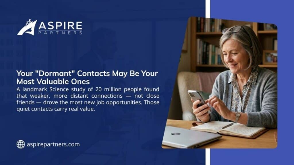 Older woman smiling at her phone while taking notes at a desk, illustrating how dormant contacts can drive the most new job opportunities.